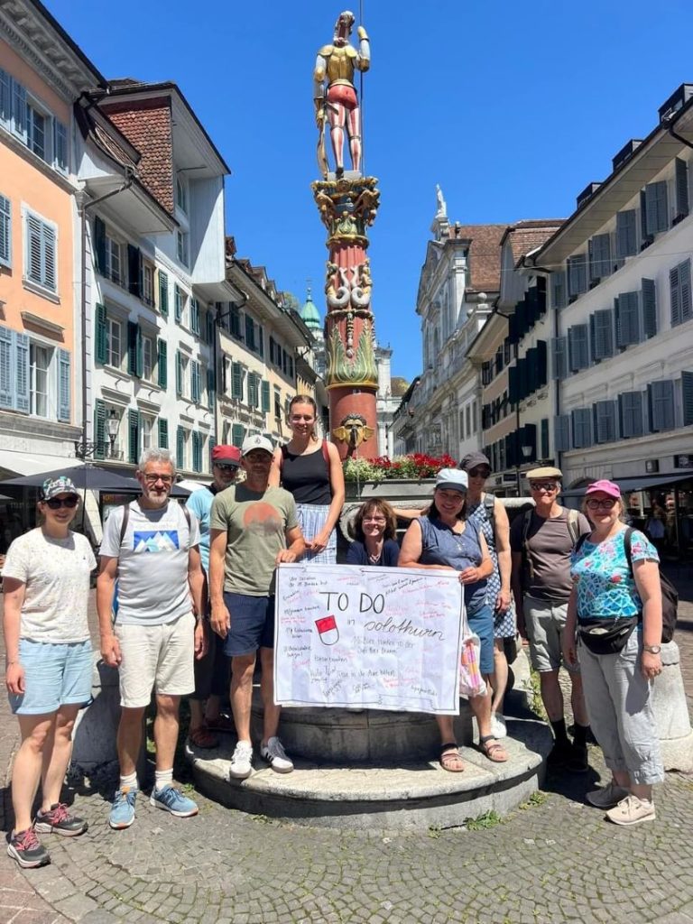 Teilnehmende am Sommercampus zeigen auf Plakat To Do in Solothurn