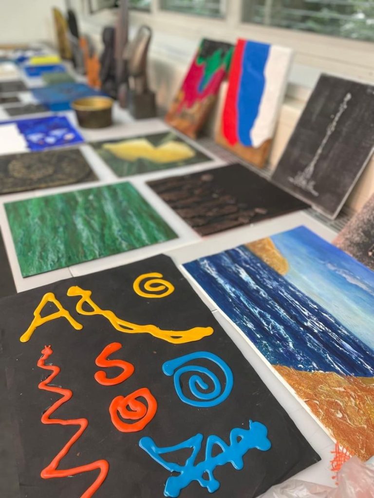 Bunte Schülerarbeiten hängen als Ausstellung im Klassenzimmer.